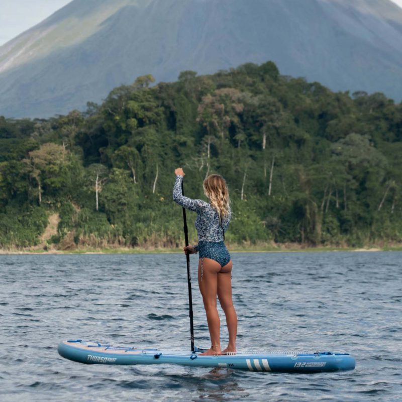 A woman stand on Thurso Surf Waterwalker 132 all-around SUP Dusk on Lake