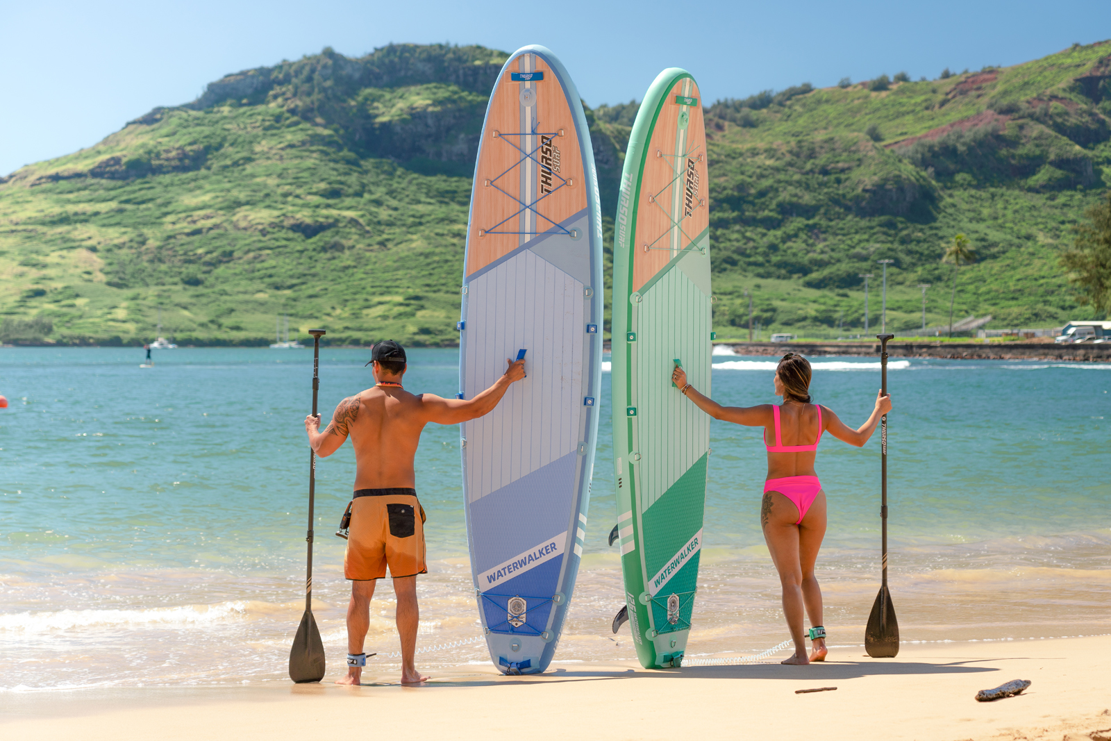 a-woman-and-a-man-holding-thurso-surf-paddle-board-respectively