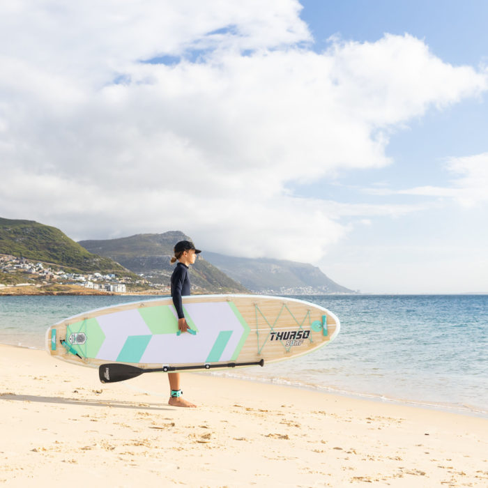 boy carrying a sup standing at the beach