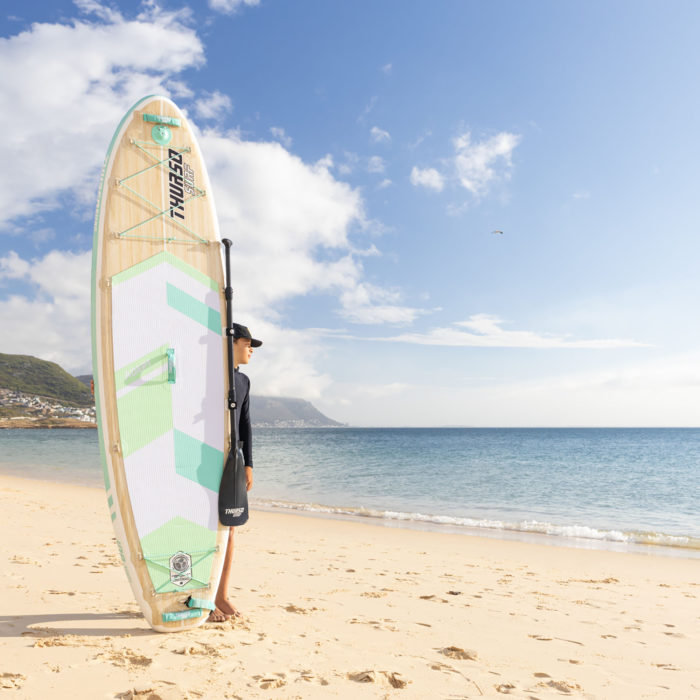 boy standing by a sup at the beach