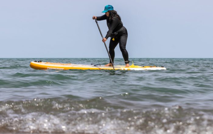 Woman paddling a SUP board through choppy water