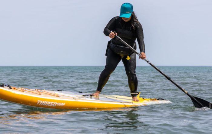Woman performs a SUP pivot turn on a Thurso Surf paddleboard